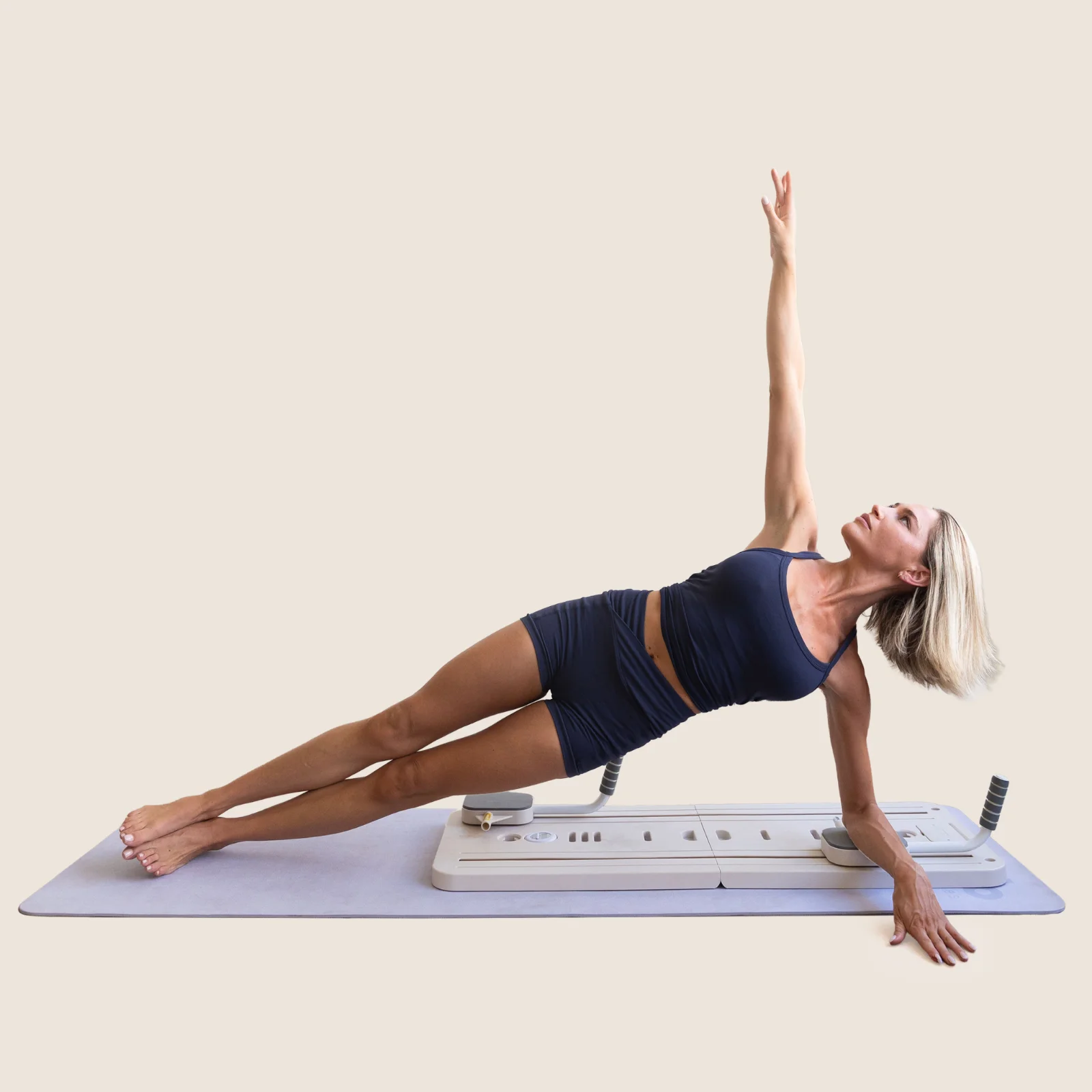 A woman holding a side plank on the flo Pilates board