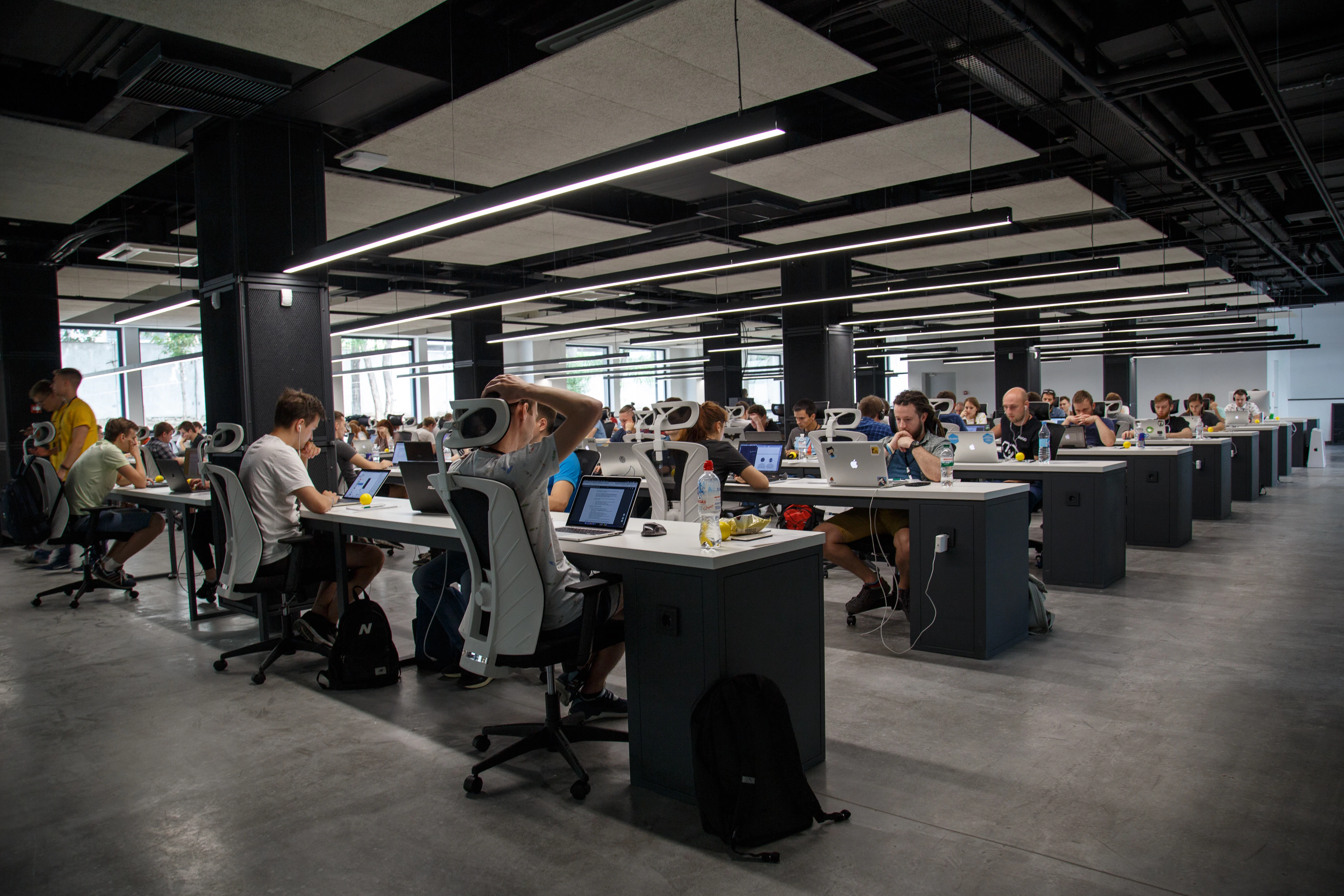 A large, bright open-plan office full of people working at long desks