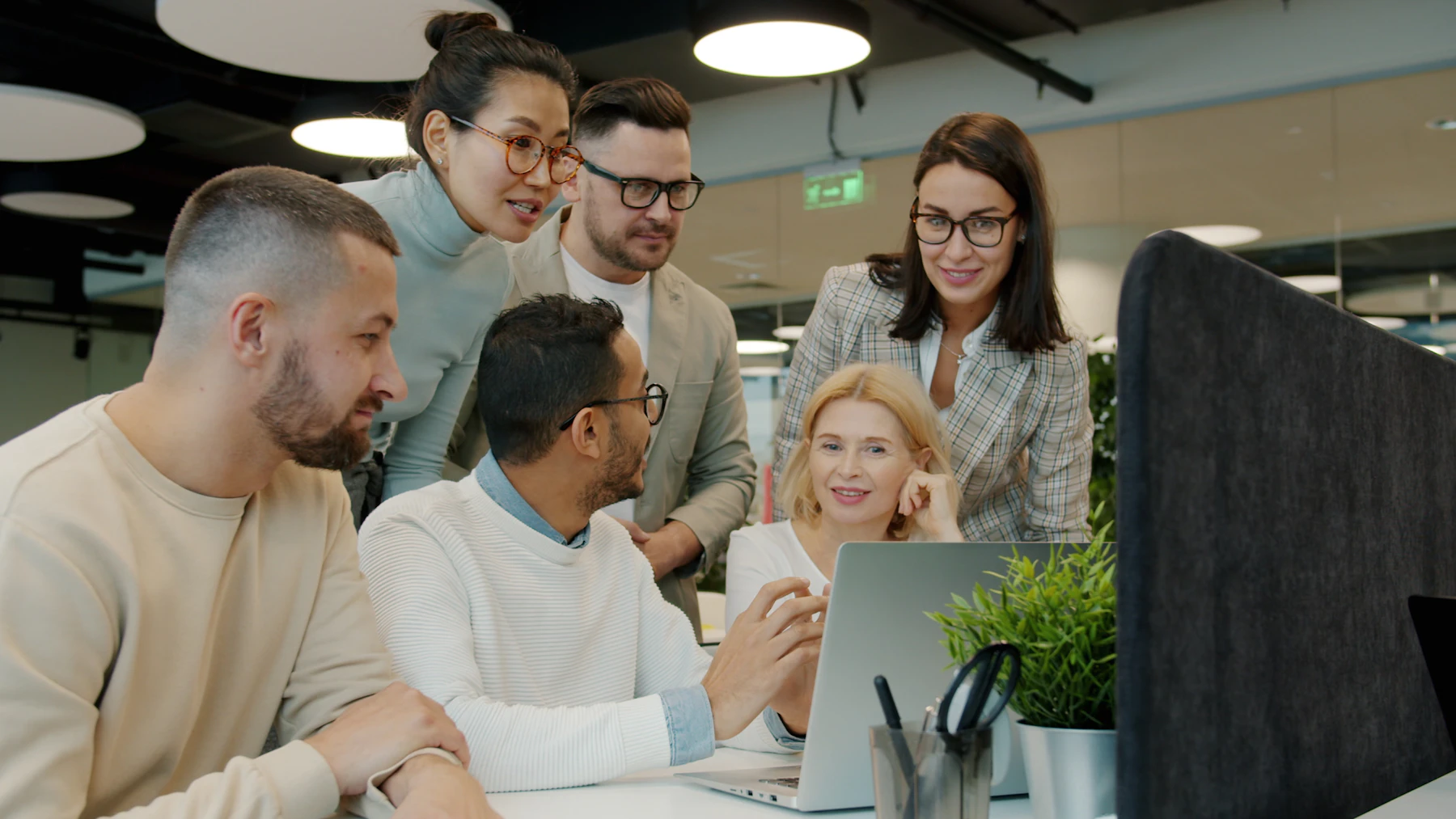 Colleagues gathered around a laptop, smiling and talking