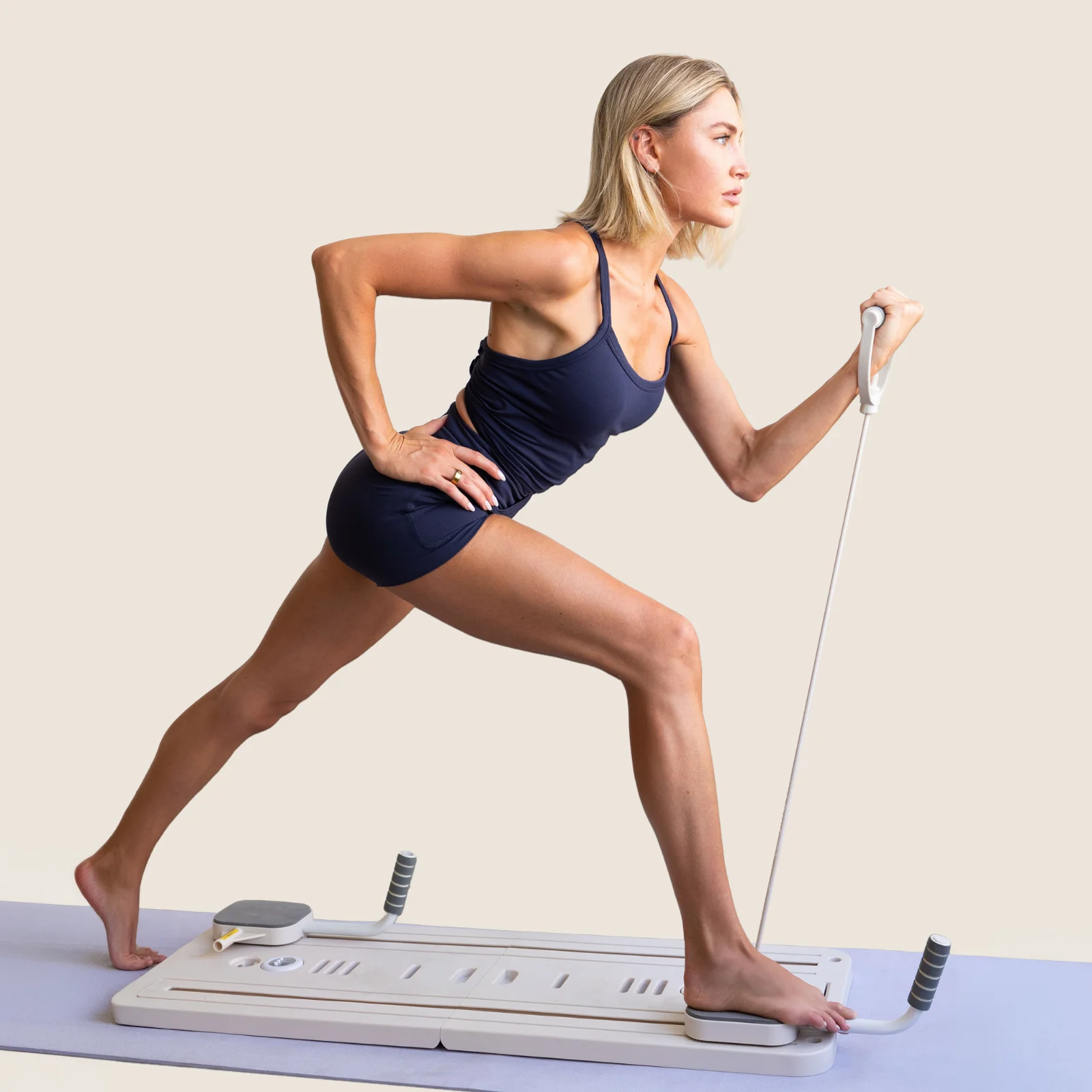 A woman in a resistance-band lunge on the flo Pilates board